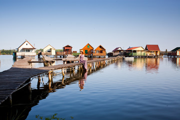 Fototapeta premium woman walking on the planks at floating village on lake Bokod, Hungary