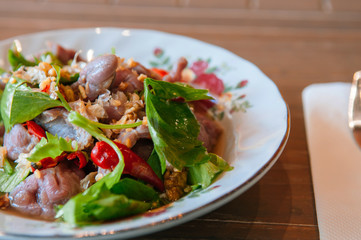 Thai food on dinner table, spicy beef salad in vintage caremic plate