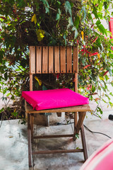 Naklejka premium Wooden chair with crooked pink pillow