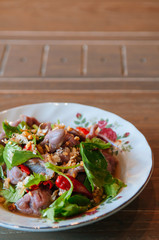 Thai food on dinner table, spicy beef salad in vintage caremic plate