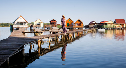 Fototapeta premium woman walking on the planks at floating village on lake Bokod, Hungary