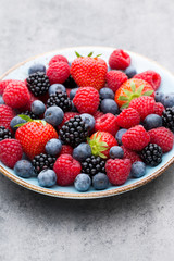 Fresh berry salad on blue dishes. Vintage wooden background.