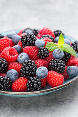 Fresh berry salad on blue dishes. Vintage wooden background.