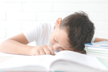 child of primary school age do homework. The boy does his homework at his desk at home. The student / pupil has been bored on the lesson. Child fell asleep during homework