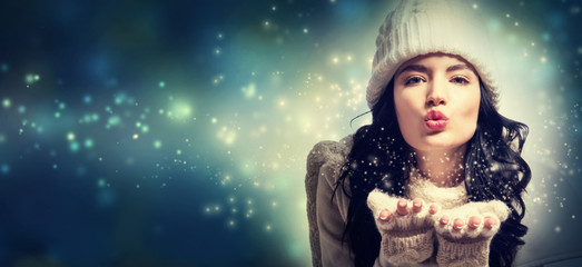 Happy young woman with winter clothes blowing a kiss