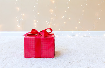 Christmas gift box on a carpet over a shiny light background