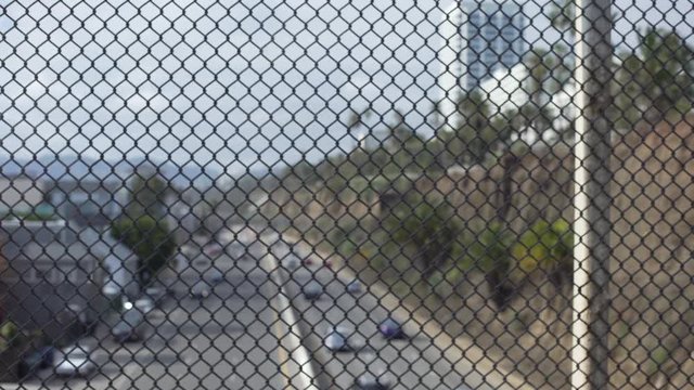 Defocused view of highway traffic through chain link fence