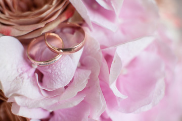 Fototapeta na wymiar Golden wedding rings on a wedding bouquet of roses