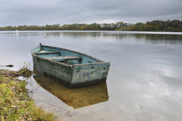 Old boat on water tied to shore 