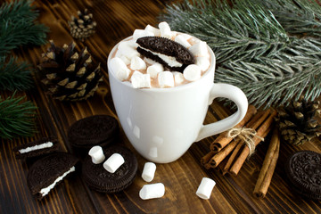 Obraz na płótnie Canvas Hot cocoa with marshmallows,chocolate cookies in the white cup and Christmas composition on the brown wooden background