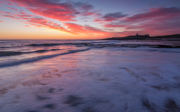 Sunrise Over Dunstanburgh Castle On The Coast Of Northumberland, England, UK.