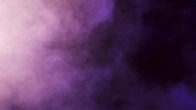 Abstract moving clouds of colorful smoke over a black background in studio. 4K footage