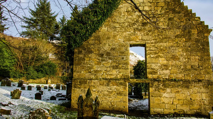 Ruin of an ivy covered chapel in a disused rural graveyard.