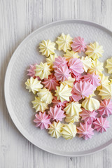 Mini meringues on gray plate over white wooden surface, view from above. Flat lay, overhead, top view.