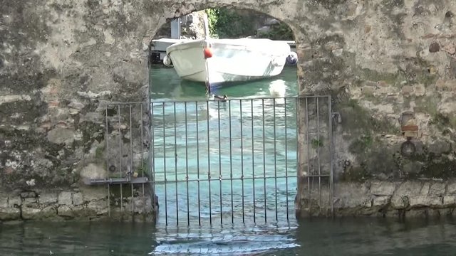 Лодка качается на воде за каменной аркой