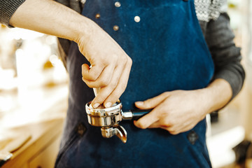 Close up of barista with tamper and piston or portafilter making espresso.