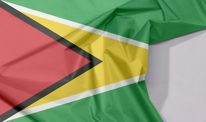 Guyana fabric flag crepe and crease with white space, a green field with the black red triangle and white golden triangle.