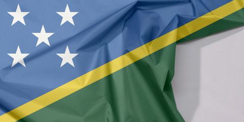 Solomon Islands fabric flag crepe and crease with white space, A thin yellow narrow diagonal stripe divided diagonally with green and blue triangle and star.