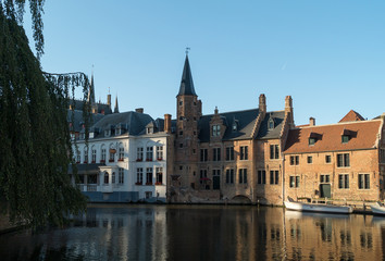 Old Bruges buildings reflecting in water canal in historical centre of Brugge