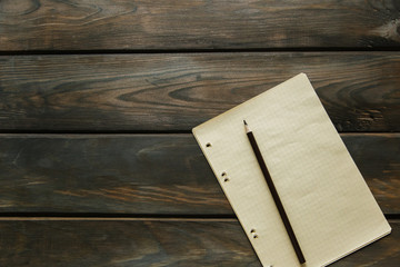 A clean sheet of paper and a pencil lay on a wooden background