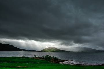 A beautiful landscape with a green field, lake and clouds