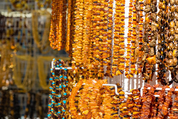 many amber beads hanging at market stand in sunny day