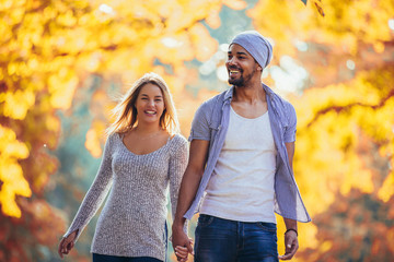 Young mixed couple walking in the autumn park