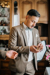 stylish groomsmen helping happy groom getting ready in the morning for wedding ceremony. luxury man...