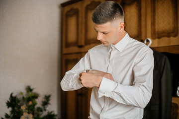 stylish groomsmen helping happy groom getting ready in the morning for wedding ceremony. luxury man...
