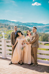 Portrait of a happy wedding guest couples laughing at camera. Bridesmaid and groomsmen outdoor portrait. Funny wedding moment. Before wedding ceremony.
