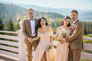 Portrait of a happy wedding guest couples laughing at camera. Bridesmaid and groomsmen outdoor portrait. Funny wedding moment. Before wedding ceremony.