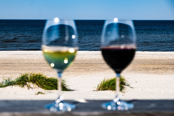 blurred red and white wineglasses on sea and beach background