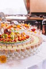 Candy bar with a lot of cookies and fruits during the wedding. chocolate fountain and wedding cake. Coktails and drink at the table