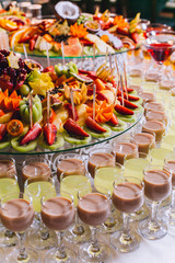 Candy bar with a lot of cookies and fruits during the wedding. chocolate fountain and wedding cake. Coktails and drink at the table