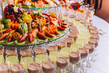 Candy bar with a lot of cookies and fruits during the wedding. chocolate fountain and wedding cake. Coktails and drink at the table