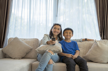 Mom and son asian couple watching TV on a sofa at home with enjoy happy