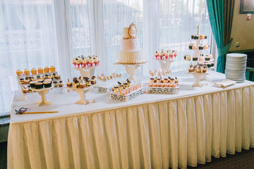 Candy bar with a lot of cookies and fruits during the wedding. chocolate fountain and wedding cake. Coktails and drink at the table