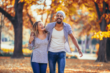 Young mixed couple walking in the autumn park