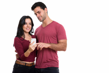 Naklejka premium Studio shot of young happy couple smiling with man using mobile 