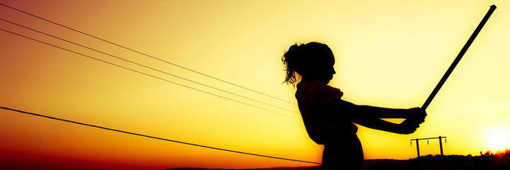 Silhouette en contre jour d'une femme pratiquant un art matial au lever du soleil