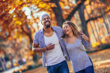 Young mixed couple walking in the autumn park