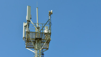 Naklejka premium Cellular antenna tower against blue sky. Top of steel mast. copy space for text