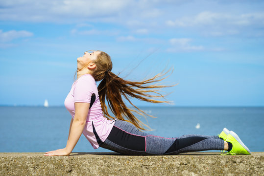 Woman doing yoga next to sea