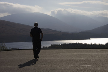 Silhouette of a man walking at viewpoint on A82 above Loch Tulla. Argyll and Bute, Lochaber, Highlands, Scotland.