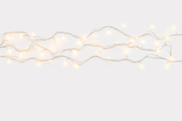 Christmas lights in warm yellow white on string over light background with copy space for text,...