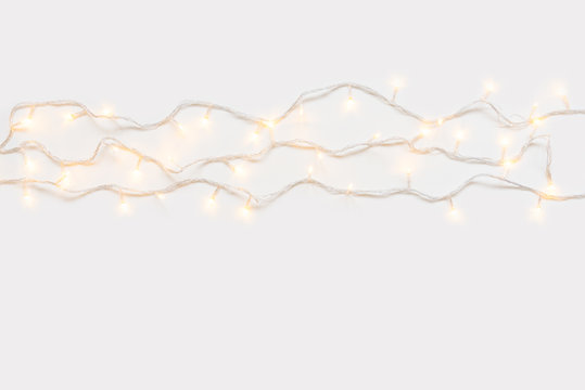 Christmas lights in warm yellow white on string over light background with copy space for text, logo decoration on Xmas eve celebration, special holidays, new year event concept
