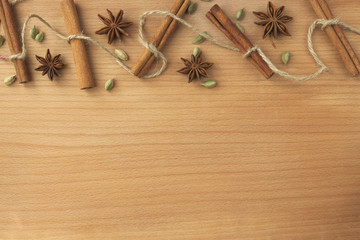 New Year spices: cinnamon, cardamom, anise, tied with a rope on the background of a wooden board