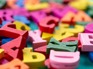 Naklejka premium clouseup of colorful wooden alphabet on green background.