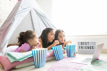 Girls Having Popcorns While Watching Movie On Laptop In Tipi Tent