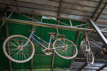 Unused old and dusty retro bicycle hanging under metal roof of home background.